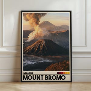 Puede incluir: Una lámina de arte mural vertical enmarcada que presenta una fotografía de paisaje del Monte Bromo en Indonesia con una columna de humo volcánico. La sección inferior incluye el texto INDONESIA MOUNT BROMO y una paleta de cinco cuadrados.