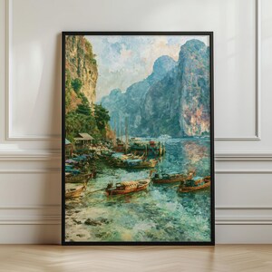 May include: A framed wall art print depicting a coastal landscape with tall limestone cliffs rising from turquoise water. Several wooden long-tail boats are moored near a rocky shoreline with lush green vegetation and small wooden structures.