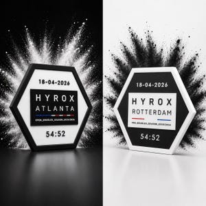 Op de afbeelding: Twee zeshoekige plaquettes met zwart-witte randen. Eén leest "HYROX ATLANTA" en de andere "HYROX ROTTERDAM". Beide tonen de datum "18-04-2026" en de tijd "54:52".