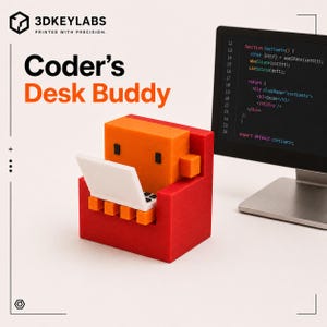 Könnte beinhalten: Eine 3D-gedruckte orangefarbene blockförmige Figur mit schwarzen quadratischen Augen sitzt in einem roten Sessel und hält einen kleinen weißen Laptop. Der Text Coder's Desk Buddy und 3DKEYLABS PRINTED WITH PRECISION steht darüber, neben einem Monitor mit Code.