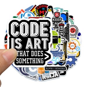 May include: A collection of assorted vinyl stickers featuring various programming and technology-themed graphics. The top sticker displays the white text "CODE IS ART THAT DOES SOMETHING" on a black background with a white border and a closing bracket.