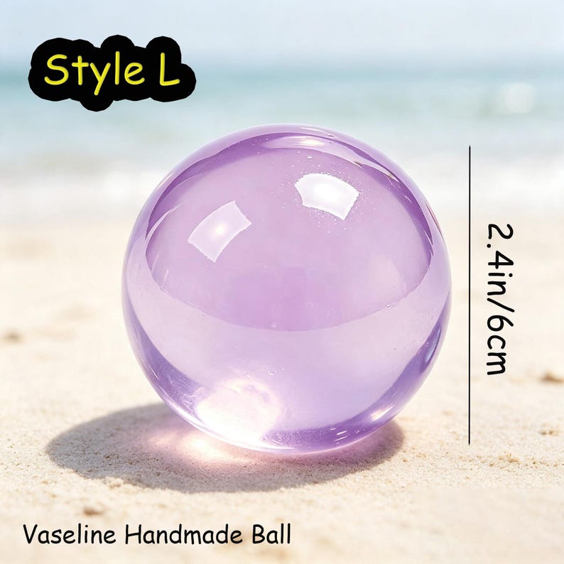 May include: A smooth, translucent purple sphere labeled Style L and Vaseline Handmade Ball. The object is shown with a vertical line indicating a diameter of 2.4 inches. The sphere has a glossy finish and reflects light on its curved surface.