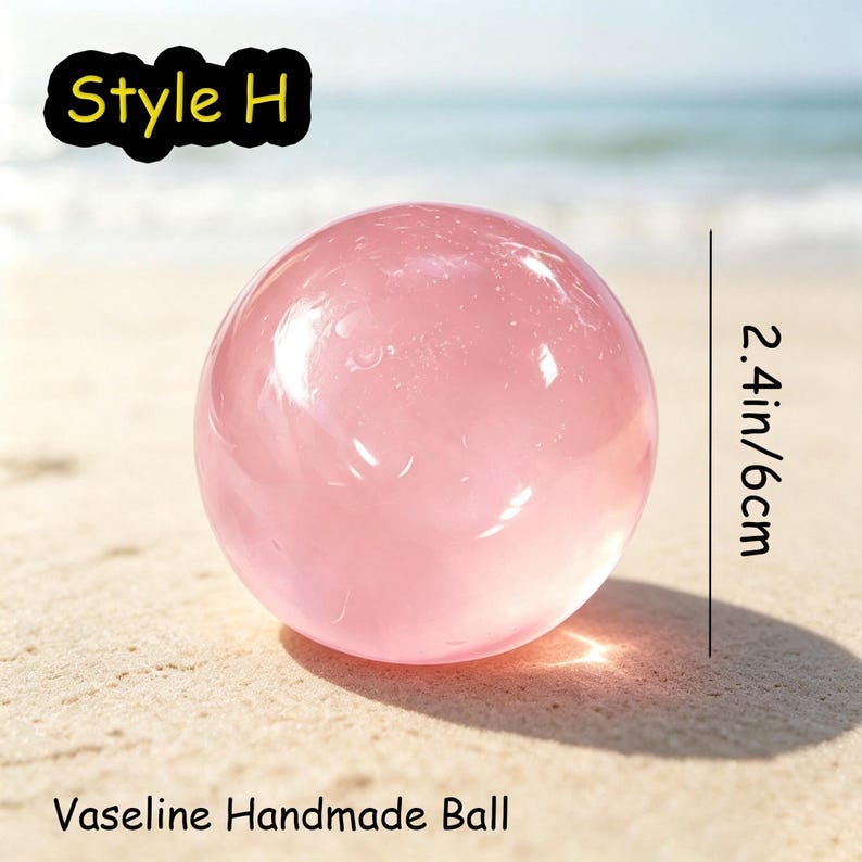 May include: A translucent, pale pink spherical object labeled Style H and Vaseline Handmade Ball. The sphere has a smooth, glossy surface and measures 2.4 inches in diameter. The object is positioned to cast a distinct shadow on the ground.
