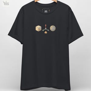 Peut inclure: T-shirt noir avec un motif graphique représentant un cube, un axe 3D, une pièce de puzzle et un globe. Le t-shirt a un col rond et des manches courtes. Le logo de la marque est visible en haut à gauche.