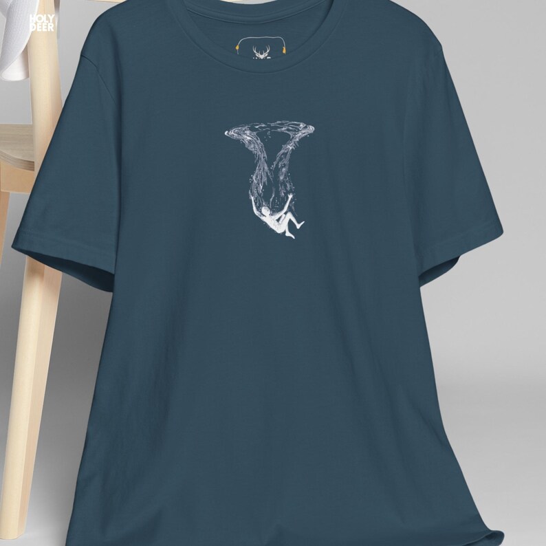 A person wearing a deep ocean tee in deep teal with a sharp, emotional underwater graphic on the front. The shirt represents a sophisticated philosophical lifestyle and is part of the HolyDeer collection, designed for those who appreciate abstract floating tops.