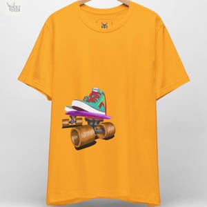 May include: A mustard yellow short-sleeve t-shirt featuring a graphic illustration of a teal and red high-top sneaker resting on a purple skateboard with large brown wheels. The inner neck label displays the text Holy Deer and HVD logo.
