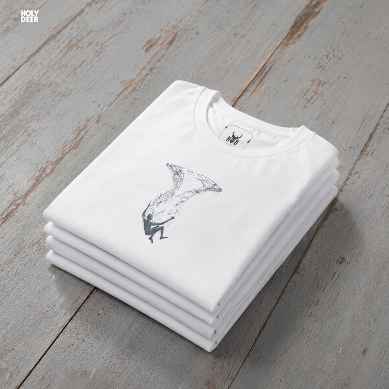 An artistic representation of the falling in water minimalist t-shirt displayed on a sleek wooden hanger to emphasize the boutique printing quality. The rich deep blue-green color and detailed conceptual art tee design create an emotional trigger for trendsetters.