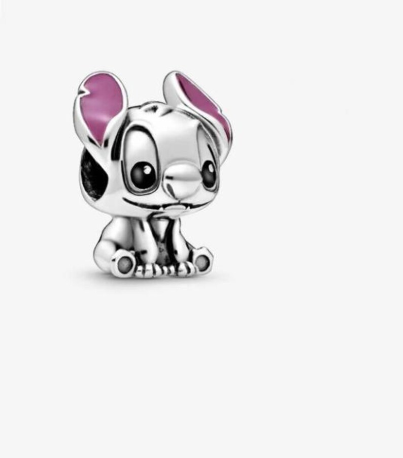 May include: A silver charm bead shaped like the character Stitch, featuring large black eyes, a small nose, and prominent ears with pink enamel detailing on the inner sections. The character is depicted in a seated position with visible paws.