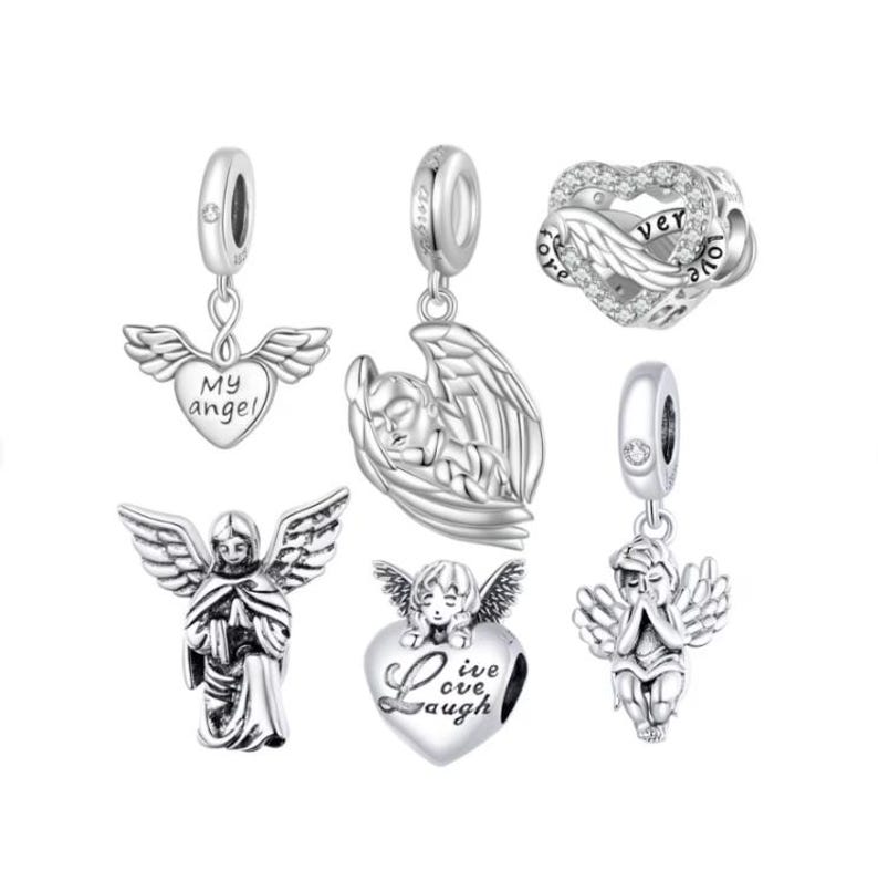 May include: A collection of silver-toned angel charms. Designs include angels with outstretched wings, a heart with wings and the words "My angel", a heart-shaped charm with "Love, Live, Laugh", and a heart-shaped charm with wings and the word "forever".