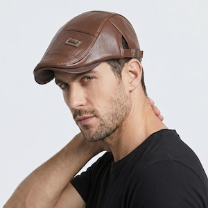 May include: A brown leather flat cap with a small rectangular accent on the front. The cap has a curved brim and an adjustable strap. The cap is a classic style, suitable for various occasions.