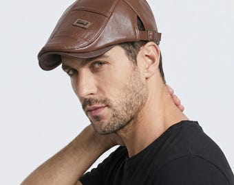 May include: A brown leather flat cap with a small rectangular accent on the front. The cap has a curved brim and an adjustable strap. The cap is a classic style, suitable for various occasions.