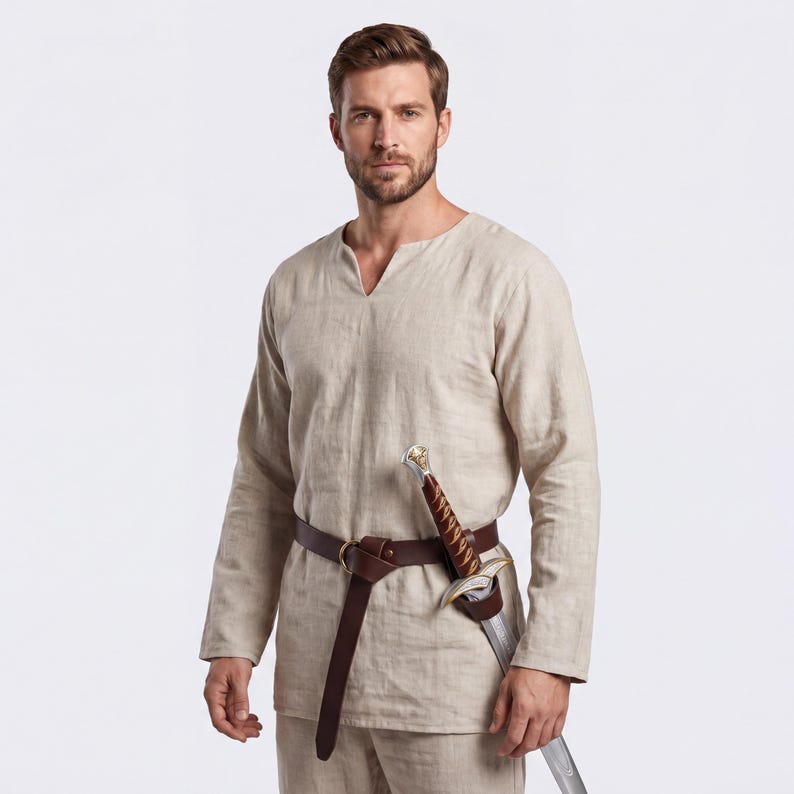Peut inclure: Une tunique en lin beige &agrave; manches longues et col en V, associ&eacute;e &agrave; un pantalon assorti. Une ceinture en cuir marron avec un fourreau d'&eacute;p&eacute;e maintient une &eacute;p&eacute;e d&eacute;corative. La tenue est adapt&eacute;e aux reconstitutions historiques ou aux &eacute;v&eacute;nements costum&eacute;s.