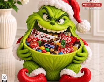 May include: A green, furry character bowl wearing a red Santa hat with white trim, filled with assorted candies including Kinder Bueno, Snickers, and KitKat bars. The text 3D Printer Files, Instant Download, and STL + 3MF Included is visible.