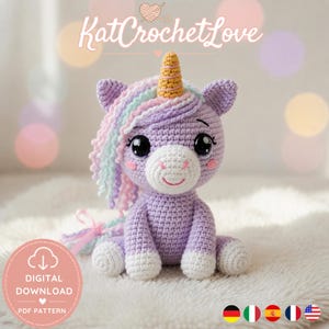 Può includere: Una bambola unicorno all'uncinetto nei toni del viola, bianco e pastello. L'unicorno ha un corno dorato, una criniera fluente e grandi occhi espressivi. Il testo "KatCrochetLove" è in alto. È disponibile un modello PDF scaricabile.