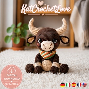 Könnte beinhalten: Ein handgehäkelter Bulle in Braun- und Beigetönen mit großen Hörnern und einem bunten Schal. Der Bulle sitzt auf einem weißen Teppich. Das Bild enthält den Text "KatCrochetLove" und eine "Digital Download" Grafik.