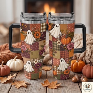 May include: Two stainless steel tumblers with black handles and clear lids, featuring a patchwork pattern of autumn-themed illustrations including white ghosts, orange pumpkins, and various colorful flowers in shades of brown, red, and yellow.