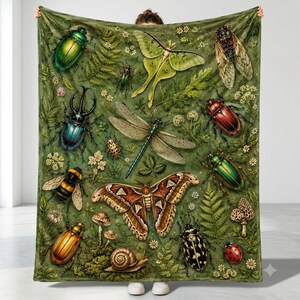 May include: A large rectangular throw blanket featuring a detailed botanical and entomological print on a green background. The design includes various insects such as beetles, a luna moth, a dragonfly, a bumblebee, a snail, and mushrooms.