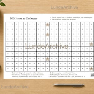 May include: A white paper titled "200 Items to Declutter" with a grid of numbered boxes. The paper includes text about decluttering and is on a wooden surface. A pen, a plant, and a notebook are also on the surface.