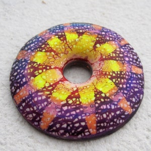 May include: A colorful ceramic donut with a yellow, orange, red, and purple design. The donut has a hole in the center and is glazed with a shiny finish.