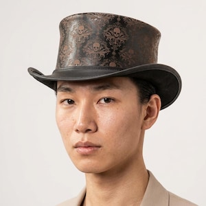 May include: A black top hat with a brown skull and floral pattern. The hat has a curved brim and a tall, cylindrical crown. The hat is made of leather and has a classic design.