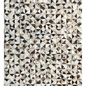 Könnte beinhalten: Ein rechteckiger Teppich, der aus zahlreichen kleinen, dreieckigen Stücken aus Rindsleder zusammengesetzt ist. Die Oberfläche zeigt ein sich wiederholendes geometrisches Muster in Schwarz, Weiß, Braun und Grau mit verschiedenen Naturhaarstrukturen.