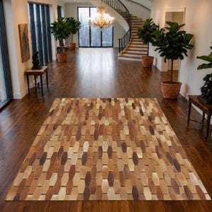 Puede incluir: Una alfombra rectangular con un patrón geométrico repetitivo de formas hexagonales alargadas en varios tonos de marrón, beige y crema. La alfombra está compuesta por piezas individuales de cuero o piel cosidas en un diseño uniforme.