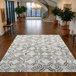Puede incluir: Una alfombra rectangular que presenta un patrón geométrico repetitivo de círculos y octágonos entrelazados en tonos gris, blanco y negro. La alfombra tiene una superficie texturizada con un diseño simétrico y consistente que cubre toda el área.