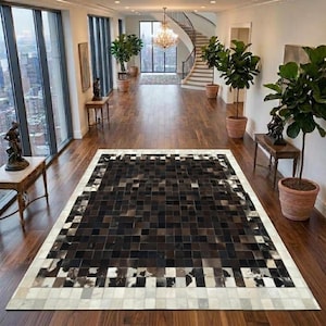 Könnte beinhalten: Ein rechteckiger Teppich mit einem Patchwork-Design aus quadratischen Fliesen in Schwarz-, Dunkelbraun- und Weißtönen. Der Teppich hat ein zentrales Gitter aus dunklen Quadraten, das von einem helleren Rand umgeben ist, auf einem Holzboden.