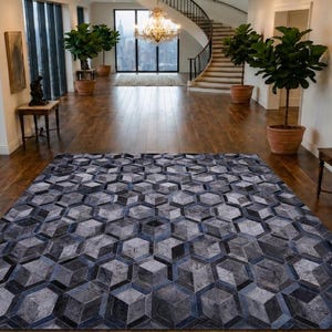 May include: A large rectangular area rug featuring a repeating geometric pattern of hexagons in shades of charcoal, slate grey, and silver. The rug is composed of individual panels that create a three-dimensional cube effect across the surface.
