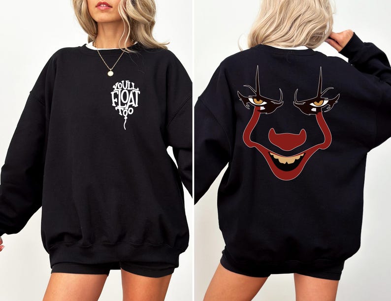 May include: A black long-sleeve sweatshirt featuring a white graphic on the front left chest that reads "YOU'LL FLOAT TOO" in the shape of a balloon. The back displays a large, detailed graphic of a clown face with red and dark features.