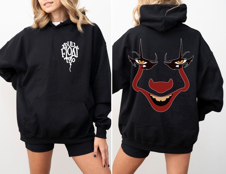 May include: A black hooded sweatshirt featuring a white balloon graphic on the front chest with the text "YOU'LL FLOAT TOO". The back of the hoodie displays a large, detailed graphic of a clown face with red makeup, yellow eyes, and a wide grin.
