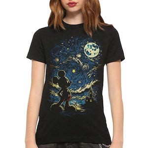 May include: A black short-sleeved t-shirt featuring a graphic print of a silhouette of Mickey Mouse standing before a swirling, starry night sky. The design includes a large yellow moon, bright stars, and a dark castle silhouette in the background.