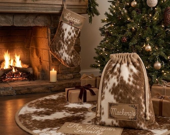 May include: A brown and white cowhide-patterned Christmas stocking with the name Lucas, a matching drawstring gift sack with the name Mackenzie, and a round tree skirt featuring the text The Morgan Family in a rustic, festive setting.