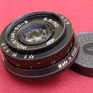 May include: Black Industar-50-2 camera lens with the text "3,5/50" and "Made in USSR". The lens has a series of numbers and markings around the edge, including "16 11 8 5,6 4 3,5 1 1,2". A black lens cap is visible.