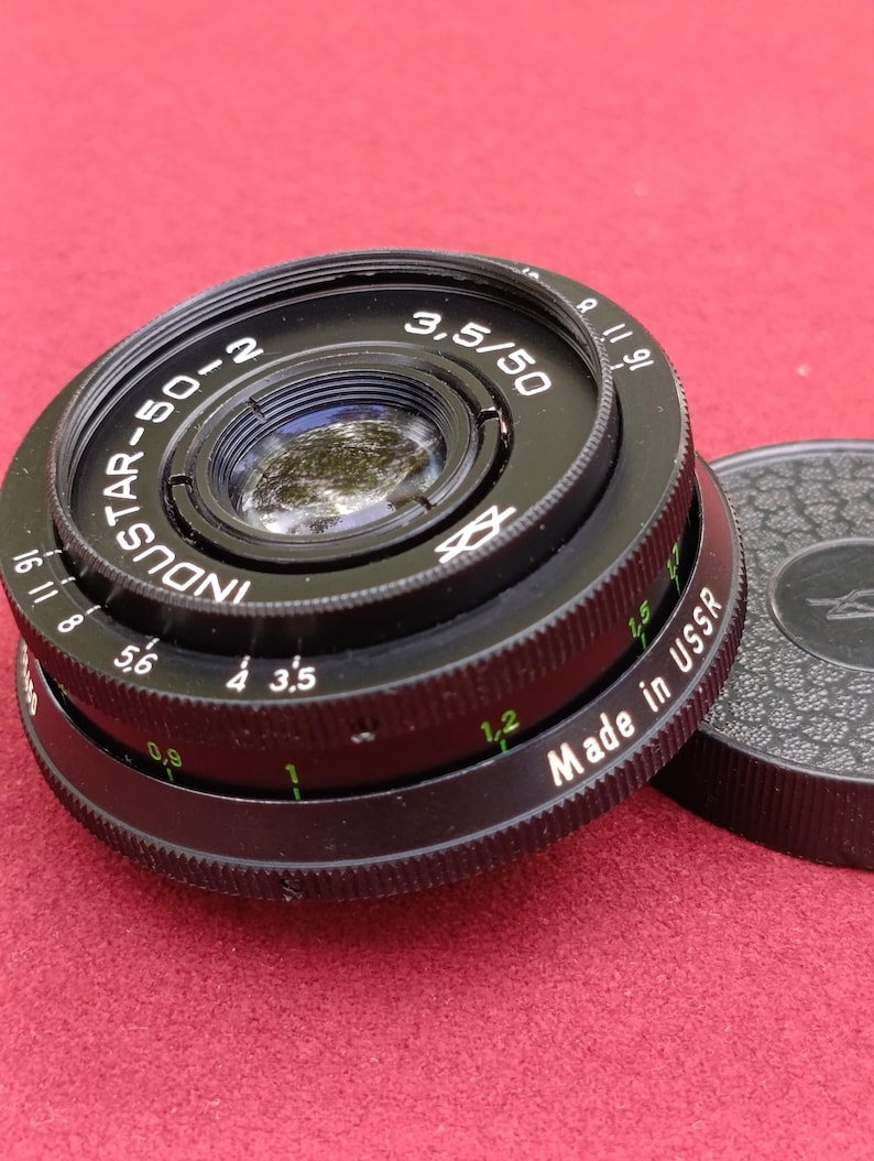 May include: Black Industar-50-2 camera lens with the text "3,5/50" and "Made in USSR". The lens has a series of numbers and markings around the edge, including "16 11 8 5,6 4 3,5 1 1,2". A black lens cap is visible.