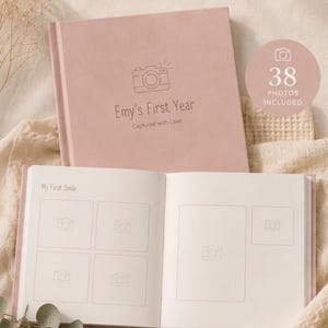 Peut inclure: Un livre de souvenirs pour bébé rose poudré avec une couverture fermée portant le texte Emy's First Year et une page ouverte montrant des cadres photo intitulés My First Smile. La couverture inclut une icône d'appareil photo et le texte 38 PHOTOS INCLUDED. Le design présente du texte sur les albums photo personnalisés et des instructions pour envoyer des photos à imprimer.