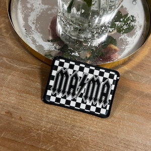 May include: Black and white checkered patch with the word "mama" in a stylized font.