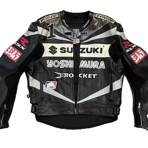 Puede incluir: Una chaqueta de moto de cuero en blanco y negro con los logotipos de Suzuki y Yoshimura, el número 1, la marca Dunlop y el texto Rocket. La chaqueta incluye bolsillos con cremallera, correas laterales ajustables y varios parches de carreras.