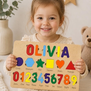 Könnte beinhalten: Holz-Lernpuzzle mit dem Namen "OLIVIA" in bunten Buchstaben. Das Brett zeigt Formen, die Zahlen 0-9 und ihre entsprechenden Wörter. Das Puzzle ist für das frühe Lernen und spielerisches Lernen konzipiert.