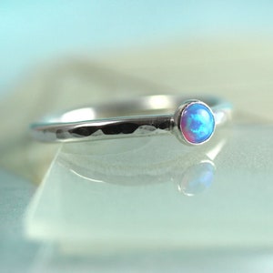 May include: A silver hammered band ring with a small blue opal gemstone.
