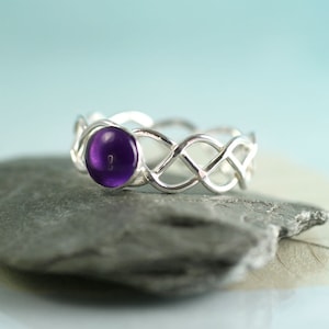 May include: A silver ring featuring a Celtic knot design and a purple amethyst gemstone.