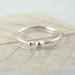 Puede incluir: Un anillo de plata con dos cuentas redondas a cada lado de la banda.