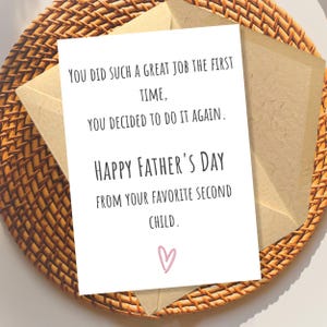 May include: A white greeting card with black text that reads: You did such a great job the first time, you decided to do it again. Happy Father's Day from your favorite second child. A small pink heart is printed at the bottom of the card.