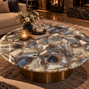 Round gray agate coffee table top with layered gray, charcoal, cream, and warm brown stone patterns, displayed in a luxury living room.