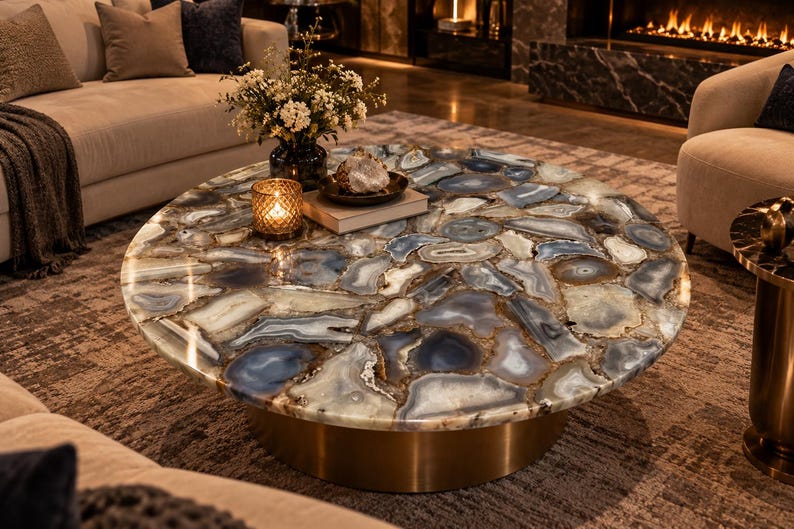 Round gray agate coffee table top with layered gray, charcoal, cream, and warm brown stone patterns, displayed in a luxury living room.