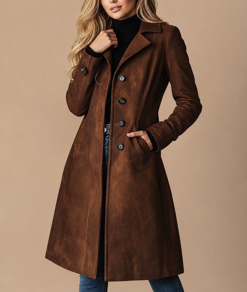 May include: A brown suede coat with a classic design. The coat features a notched collar, button closure, and pockets. The coat is knee-length and has a tailored fit. The coat is a rich, warm brown color.