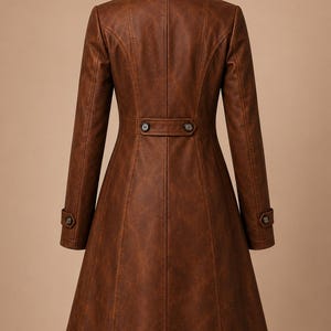 May include: A brown, faux leather coat with a classic design. The coat features a notched collar, long sleeves, and a button closure at the waist. The coat has a flared skirt and button details on the sleeves.
