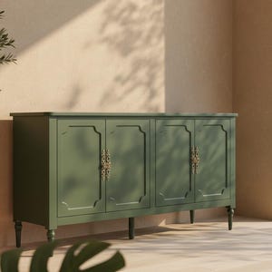May include: A green cabinet with four doors and ornate gold-colored handles. The cabinet is set against a neutral wall with sunlight casting shadows. A potted olive tree and a large leaf plant are in the foreground, suggesting a natural theme.