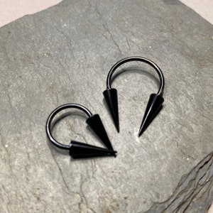 Tragus Rook Snug Daith Ring mit Spikes - Tragus Rook Snug Daith - Schwarzes 14G Hufeisen 3/8 Zoll mit 4 x 12 mm Spikes