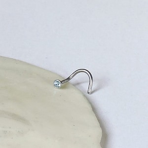 May include: A silver nose ring with a small, light blue gemstone.